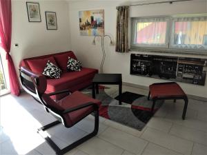 sala de estar con sofá rojo y silla en sehr schöne Ferienwohnung in Ebersberg bei München, en Ebersberg