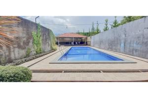 a swimming pool in a yard next to a wall at Hotel Sri Indrawati Puncak Mitra RedDoorz in Bogor