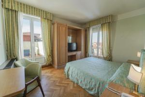 een hotelkamer met een bed, een stoel en een raam bij HG Hotel Cappelli in Montecatini Terme