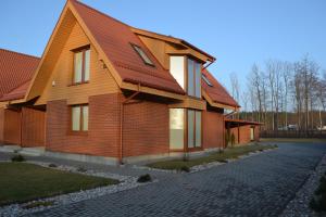 uma casa com um telhado vermelho numa estrada de tijolos em Vila Vėtrūnė em Šventoji