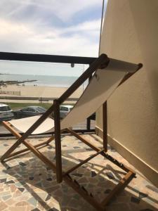 a chair sitting on a balcony looking out at the beach at Hôtel Café Miramar in Le Grau-du-Roi