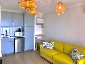 a living room with a yellow couch and a kitchen at Hôtel Café Miramar in Le Grau-du-Roi
