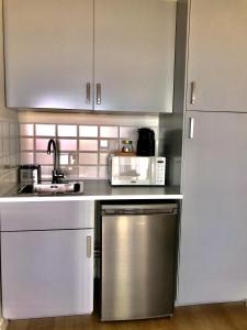 a kitchen with white cabinets and a stainless steel dishwasher at Hôtel Café Miramar in Le Grau-du-Roi