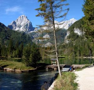 a person sitting on a bench next to a lake with a mountain at Ferienwohnung Pyhrgasblick in Rosenau am Hengstpass