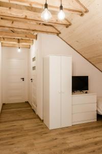 an attic bedroom with white cabinets and a tv at Daszówka Bieszczady in Ustrzyki Dolne