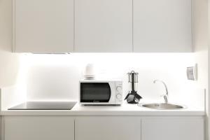 a white kitchen with a microwave and a sink at Palazzo dei Ciompi Suites in Florence