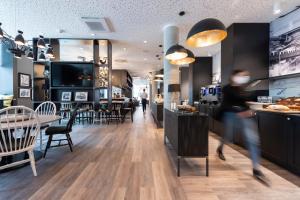 a restaurant with a person walking past a counter at HARBR. Hotel Ludwigsburg in Ludwigsburg