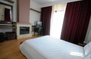 a bedroom with a white bed and a fireplace at Nostos Hotel in Afitos