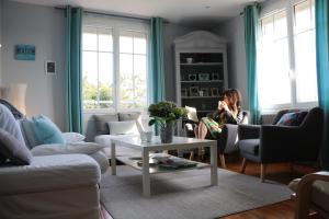 a woman is sitting in a living room at La Source in Hermanville-sur-Mer