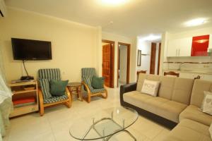 a living room with a couch and chairs and a tv at Two bedroom apartment in beachfront complex with pool in Playa de Las Américas. in Playa de las Americas