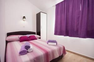 sypialnia z łóżkiem z fioletowymi ręcznikami w obiekcie Apartment Perla w mieście Brodarica