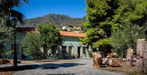 a green building with trees and a mountain in the background at Arsinoe - Cosy guesthouse- in Methana