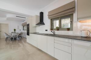 a kitchen with white cabinets and a dining table at Villa Anna in Zakynthos Town