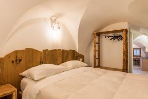 Schlafzimmer mit einem weißen Bett mit einem Kopfteil aus Holz in der Unterkunft Logge dei Paroloti Paolo in San Lorenzo in Banale