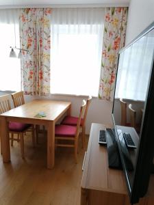 a dining room with a table and a laptop on a desk at Appartement Alpenglück in Aich