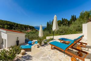 een patio met blauwe ligstoelen en een parasol bij Holiday Home Likva - Sutivan - Island of Brač in Sutivan