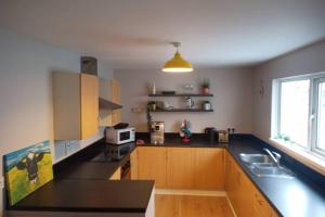 une cuisine avec des placards en bois et un comptoir noir dans l'établissement Argyle House, 10 minute walk from city centre, à Derry Londonderry