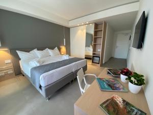 a bedroom with a bed and a table and a television at Sicilia's Art Hotel & Spa in Acitrezza