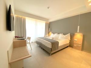 a bedroom with a bed and a desk and a television at Sicilia's Art Hotel & Spa in Acitrezza