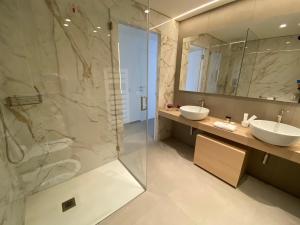 a bathroom with two sinks and a glass shower at Sicilia's Art Hotel & Spa in Acitrezza