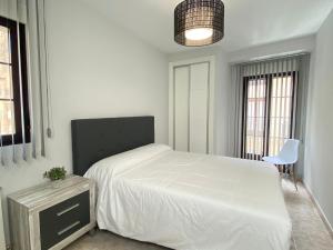 1 dormitorio con 1 cama blanca y 1 silla en Apartamento Serranos Centro Histórico, en Salamanca