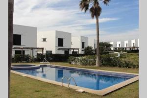 a swimming pool in front of a house with a palm tree at Villa Blanca Punta Grossa in Punta Grossa