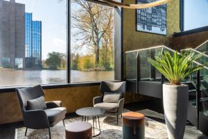 a waiting area with chairs and a table and windows at Radisson Hotel & Suites Amsterdam South in Amstelveen