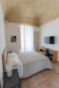 um quarto com uma grande cama branca e uma televisão em Antica Pepice em Matera
