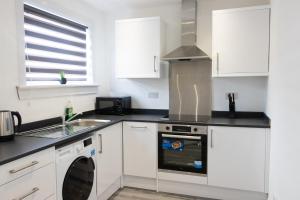 cocina con armarios blancos y lavavajillas en Vion Apartment - Farquhar, en Aberdeen