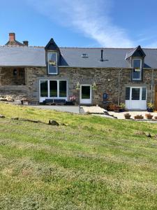 une maison en pierre avec une pelouse devant elle dans l'établissement Ash Tree, à Vire