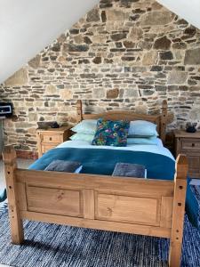 a bedroom with a wooden bed with a stone wall at Ash Tree in Vire