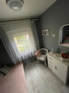 een slaapkamer met een bed, een dressoir en een raam bij Ágnes Nyaralóház in Balatonmáriafürdő