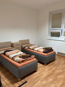 3 camas en una habitación con suelo de madera y ventana en Apartmanový byt v priemyselnej zóne, en Vranov nad Topľou