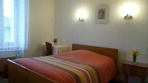 ein Schlafzimmer mit einem Bett und einem Tisch mit Blumen in der Unterkunft Hotel La Vie En Rose in Le Brugeron