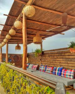 eine Holzbank unter einer hölzernen Pergola mit Kissen in der Unterkunft Color Safrà in Marrakesch