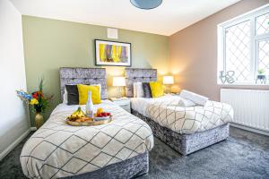 a bedroom with two beds and a bowl of fruit at Central Leamington Spa House with Free Parking, Fast Wifi, Smart TV with Free Netflix and Garden by Yoko Property in Leamington Spa