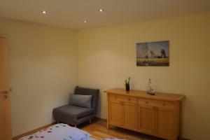 a bedroom with a chair and a desk and a painting at Ferienhaus Schönebühl in Oberreute +12 photos