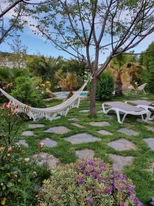 um jardim com rede de descanso, mesas e flores em La Placeta Guesthouse em Pórtugos