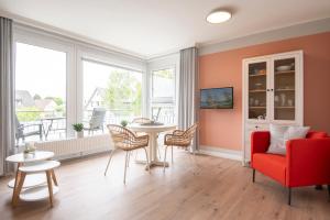 ein Wohnzimmer mit einem roten Sofa, einem Tisch und Stühlen in der Unterkunft Haus Panorama Wohnung 16, Steinmatz in Grömitz