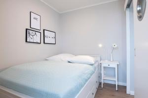 ein weißes Schlafzimmer mit einem Bett und einem Beistelltisch in der Unterkunft Haus Panorama Wohnung 16, Steinmatz in Grömitz