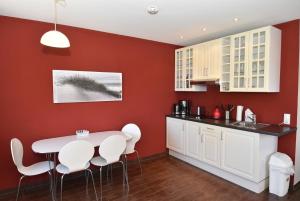 eine Küche mit roten Wänden sowie einem Tisch und Stühlen in der Unterkunft fewo1846 Strandresidenz Wassersleben - Strandkoje - komfortables Studioapartment mit Meerblick am Strand in Harrislee