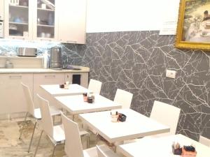 2 mesas en una cocina con sillas blancas y una pared en Giulietta nei Sassi, en Matera