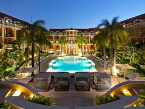 a resort with a large swimming pool with palm trees at Sofitel Legend Santa Clara Cartagena in Cartagena de Indias