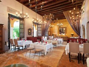 un comedor con mesas y sillas blancas y lámparas de araña en Sofitel Legend Santa Clara Cartagena, en Cartagena de Indias