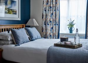 a bedroom with a bed with blue walls and a window at The Barrington Boar in Ilminster