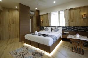 a bedroom with a large bed and a table at Hotel Elysian Residency in Ahmedabad