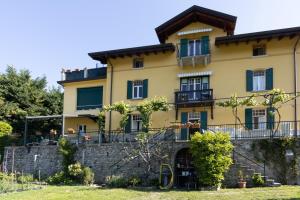 a large yellow house with a stone wall at Conca Verde Appartaments in Bellagio