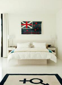 a white bedroom with a bed with a flag on the wall at Bungalow Hotel in Long Branch