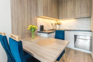 HollyŁódź Apartment NETFLIX في لودز: مطبخ مع طاولة خشبية وكراسي زرقاء