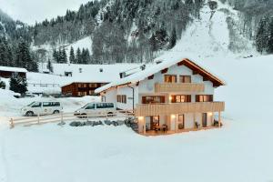 une maison dans la neige avec deux voitures garées dans l'établissement Chalet Klösterle, à Wilden